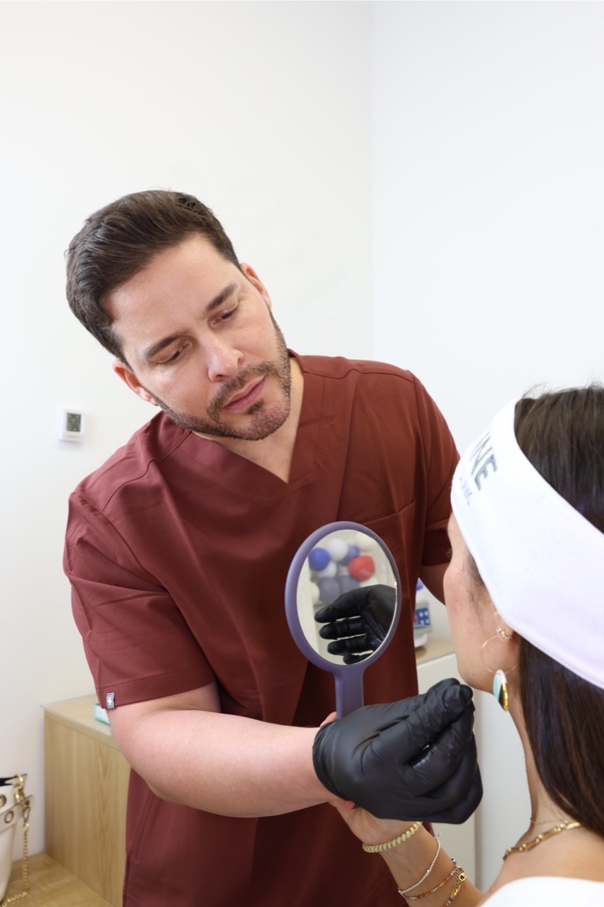 Valoración facial con espejo de mano en Clínica Holivine, con un profesional que lleva guantes